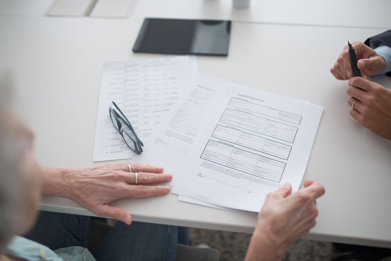 Close-up view of two individuals reviewing documents and forms in an office setting.