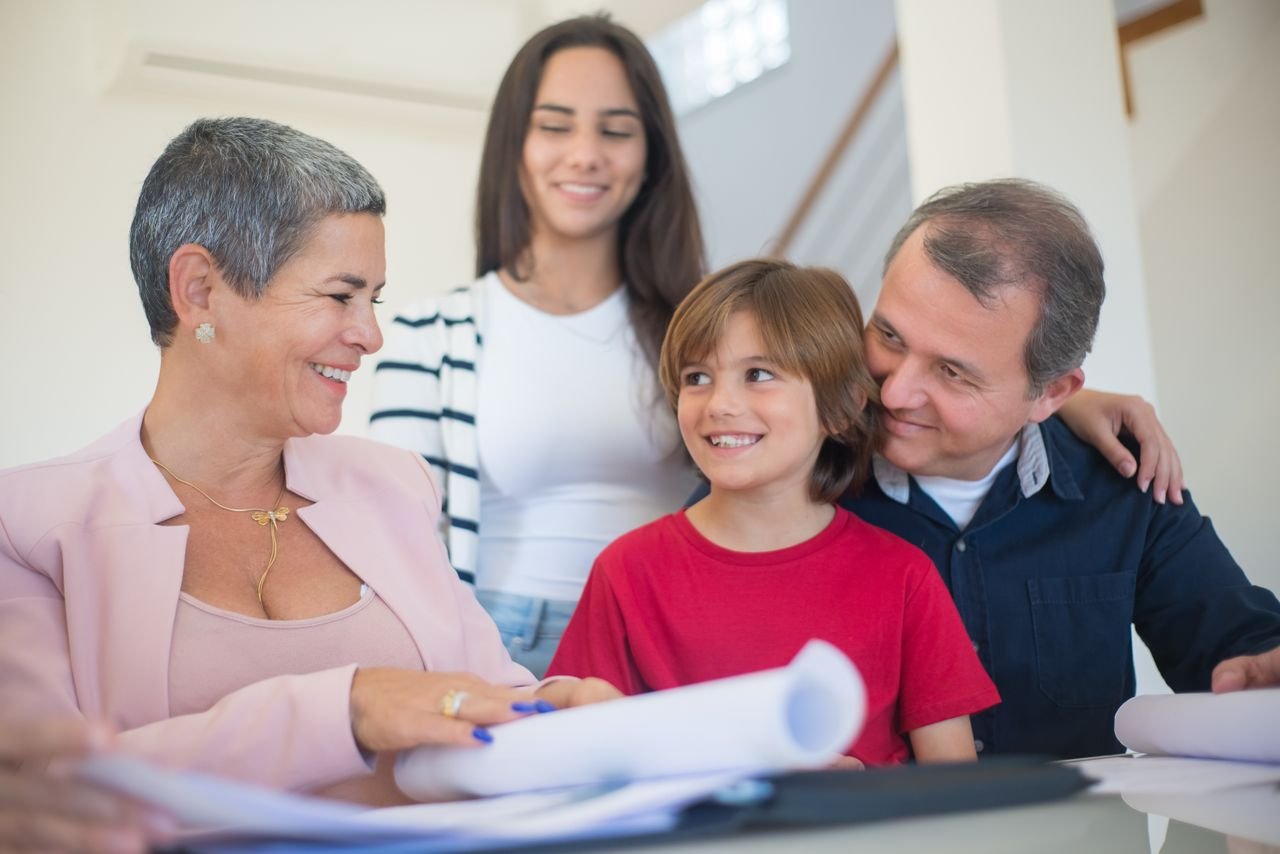 about-03 Smiling family indoors signing real estate documents. Friendly interaction and teamwork.