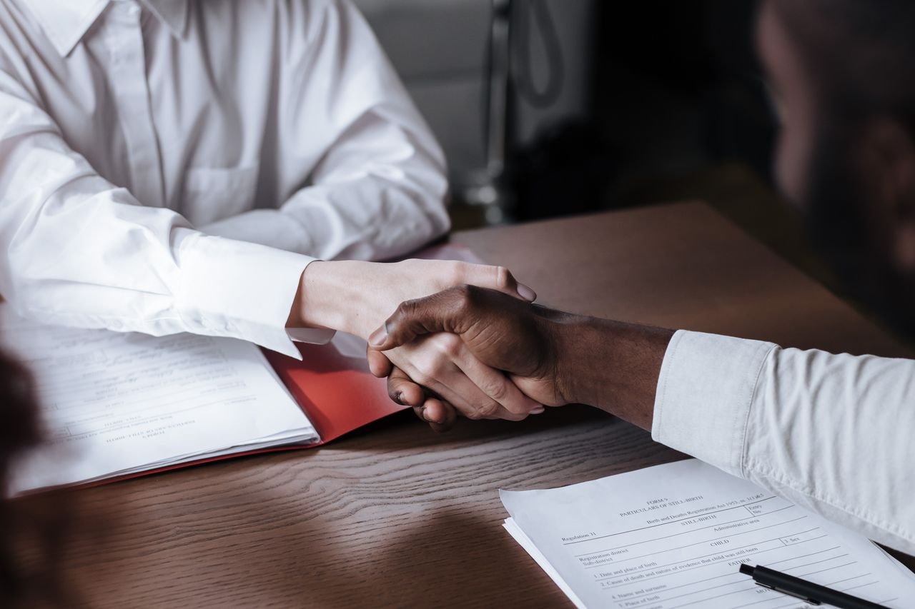 services-03 Close-up of a diverse business handshake over documents, symbolizing agreement and collaboration.